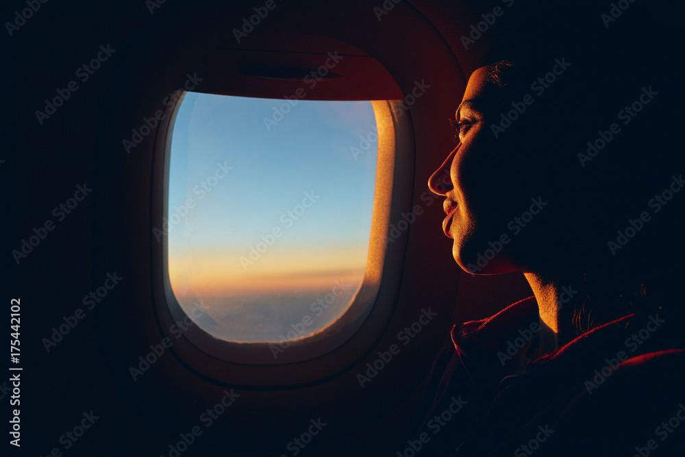 Fototapeta premium woman looking at sky with clouds from the airplane window. sunset with a height of 10 000 km. woman face close up