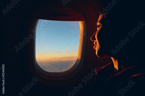woman looking at sky with clouds from the airplane window. sunset with a height of 10 000 km. woman face close up