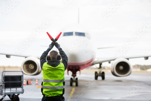 Ground Worker Signaling To Airplane On Runway photo