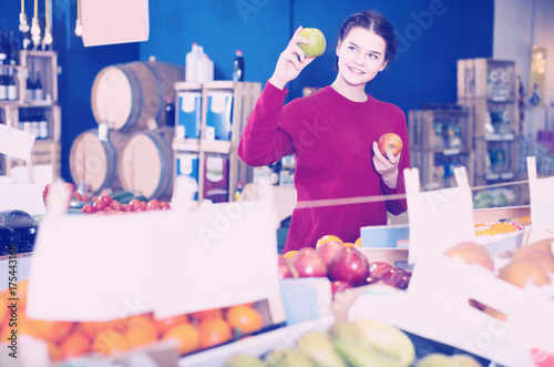 Portrait of  young customer selecting apple in grocery photo