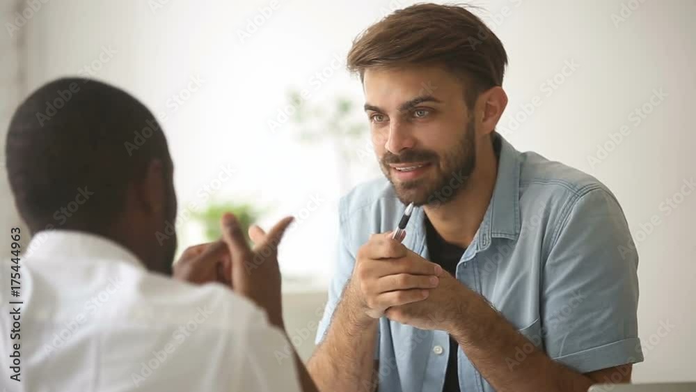 Two multiracial diverse businessmen having dispute, disagreeing during negotiations, defending different points of view while discussing teamwork, arguing debating at workplace, telling arguments