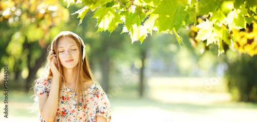 Happy Girl Listening to Headphones on a Wonderful Autumn Day photo