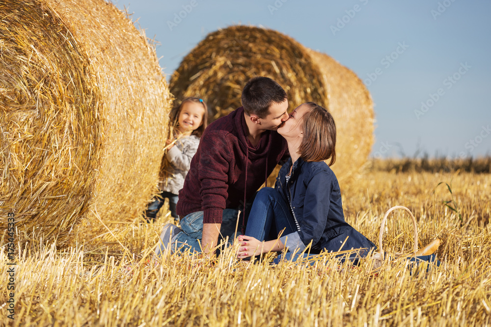 Happy young family with 2 year old girl next to hay bales in harvested field Happy young family with 2 year old girl next to hay bales in harvested field