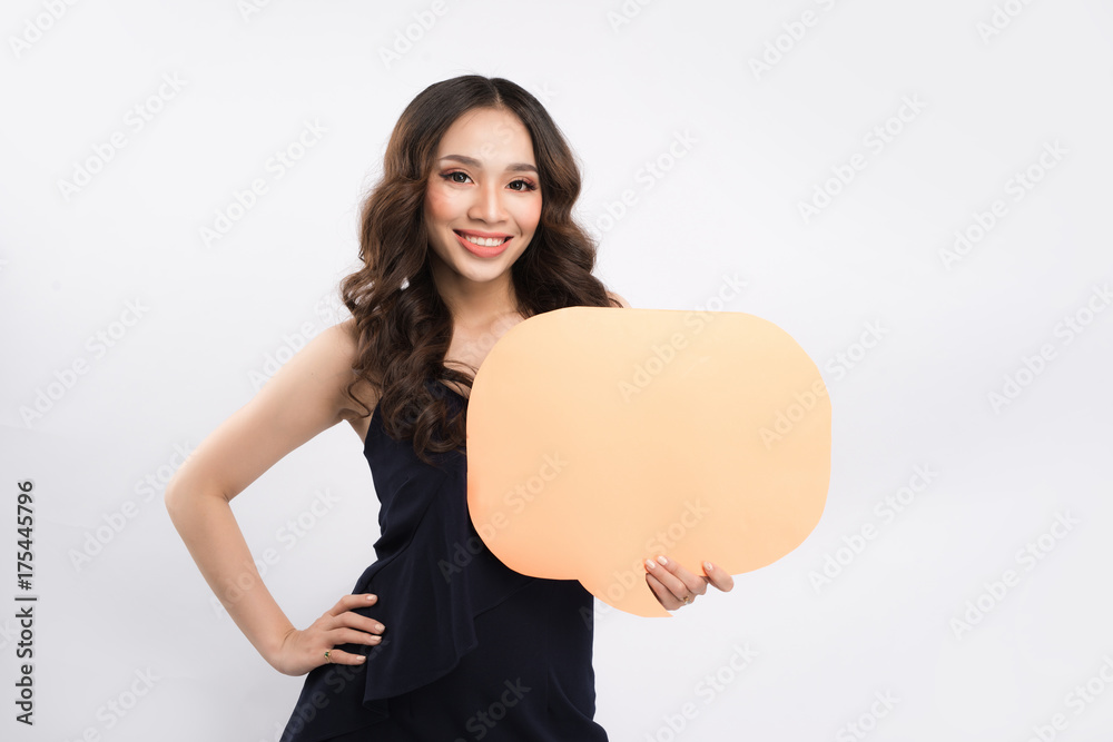 Smiling young woman holding empty speech bubble while standing on blue background Smiling young woman holding empty speech bubble while standing on blue background