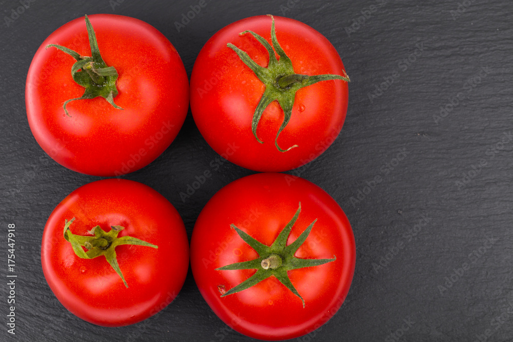 Ripe red tomatoes on black stone plate Ripe red tomatoes on black stone plate