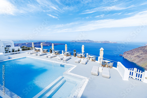Swimming pool with beautiful view on Aegean sea, Santorini, Greece at hot sunny summer day.