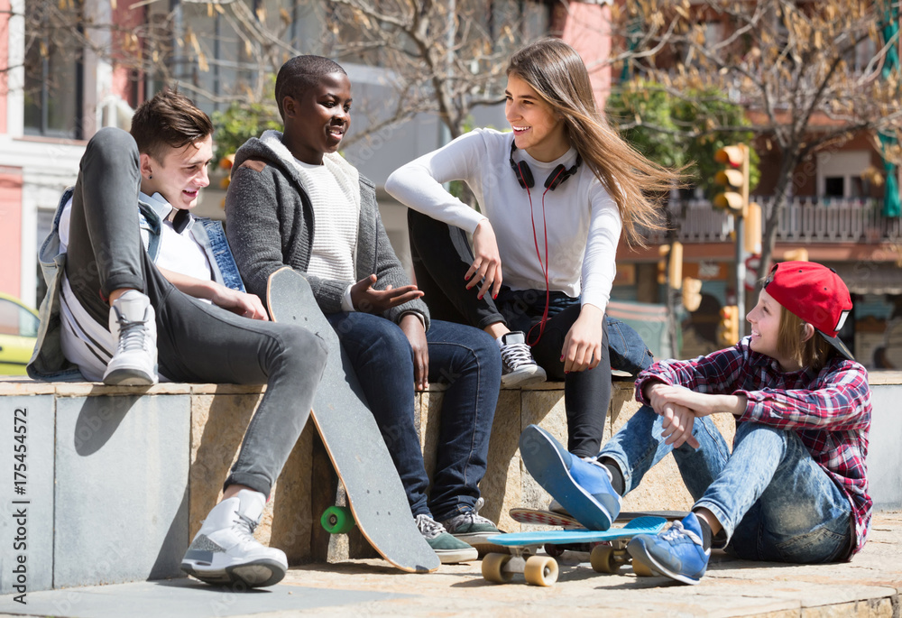 Fototapeta premium girl and three boys hanging out outdoors and discussing something