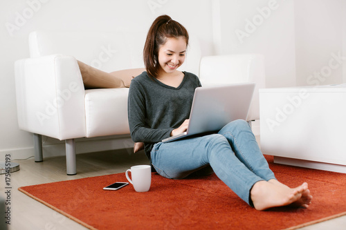 Beautiful young Asia woman working with laptop in living room