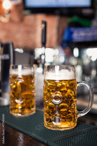 фотография Two glasses of beer on a bar table. Beer tap on background
