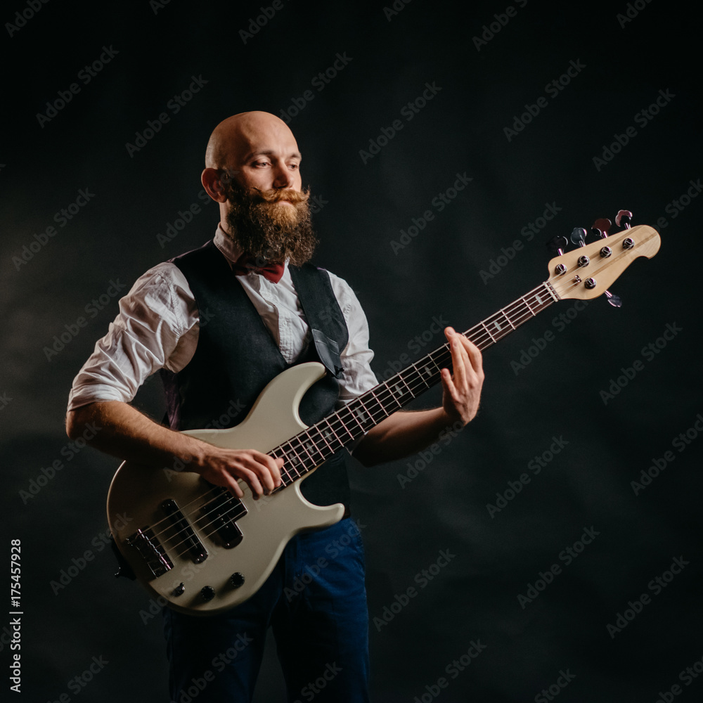 Obraz premium adult bearded man enthusiastically playing guitar on a black background