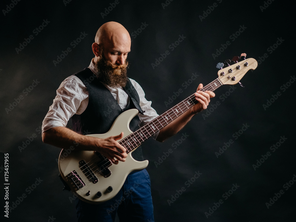 Obraz premium adult bearded man enthusiastically playing guitar on a black background