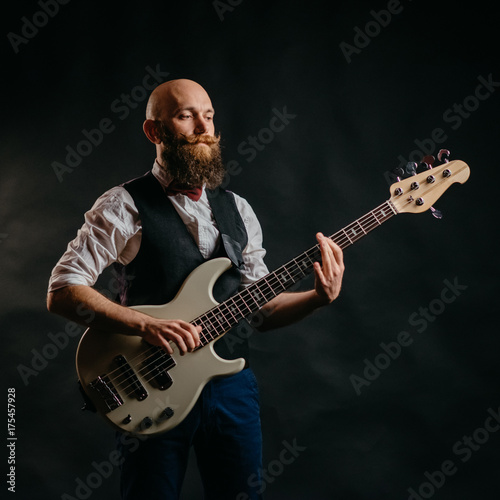 adult bearded man enthusiastically playing guitar on a black background photo
