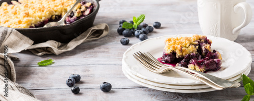 Coconut crumble on white plate with fresh apples and blueberry. Healthy food concept. Banner.