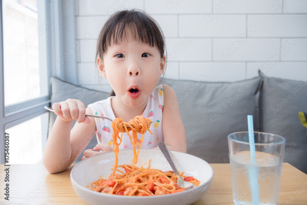 Little asian girl enjoy eating spaghetti on table at restaurant Little asian girl enjoy eating spaghetti on table at restaurant