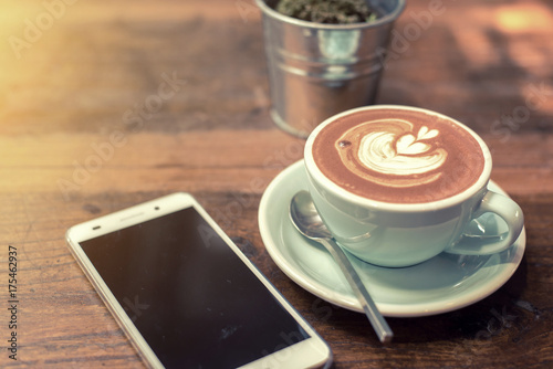 Mobile phone and coffee table on wooden table.