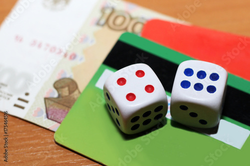 Two dice laying over a pile of money