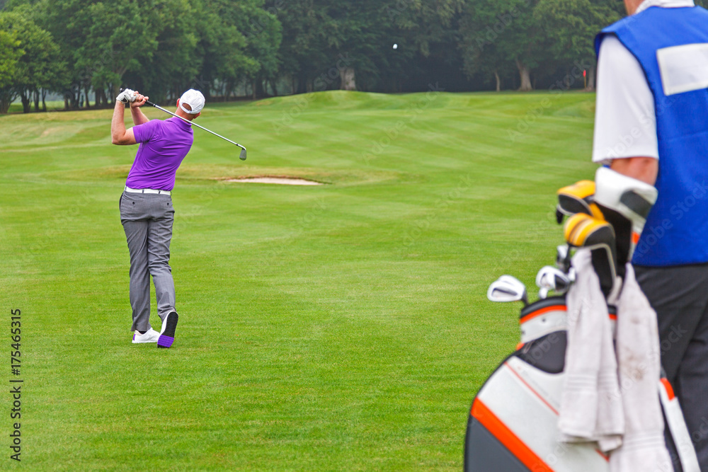 Obraz premium Pro golfer playing a shot with caddy