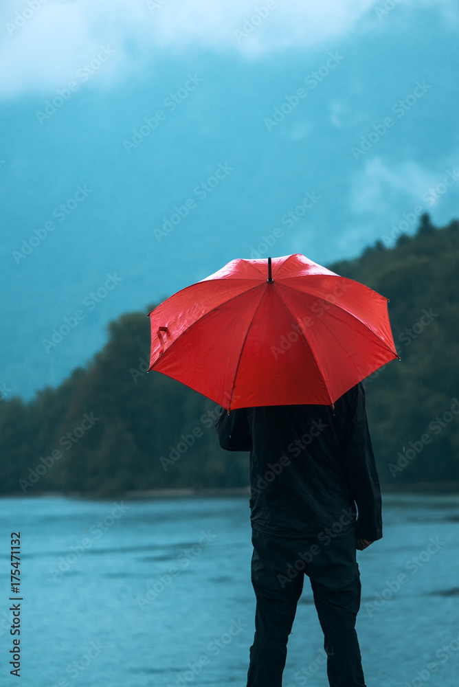 Man with red umbrella contemplates on rain