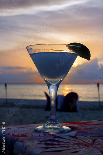 Cocktail at the beach at sunset with a pink and lavender sky.