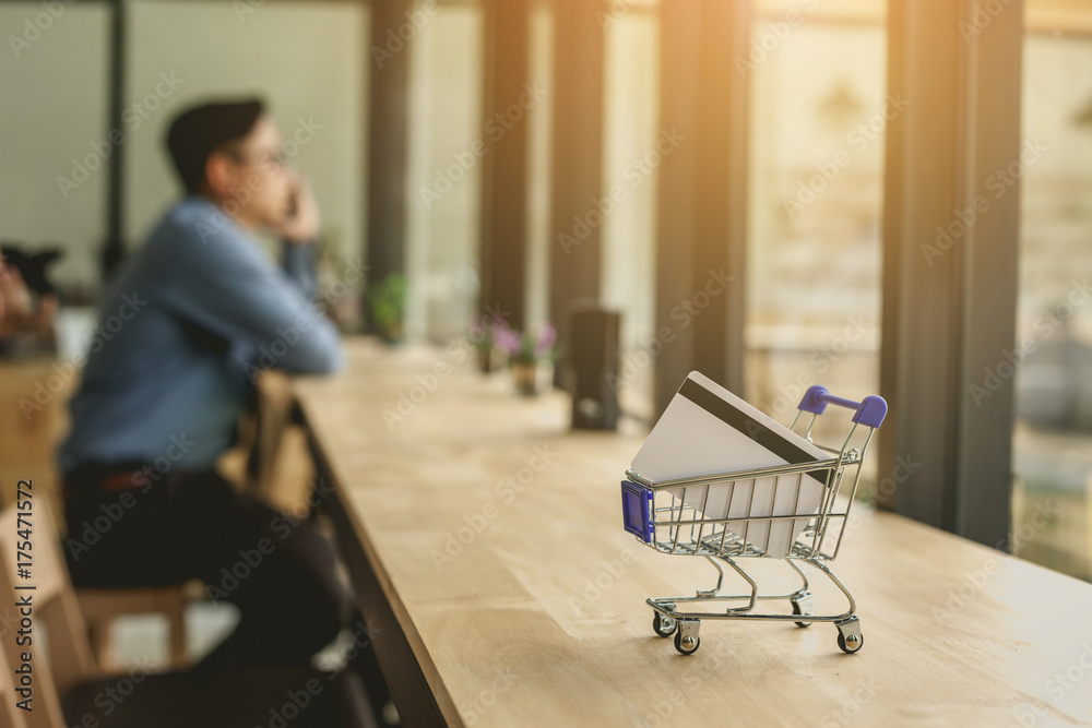 Credit Card in Shopping Cart On the table. Online Shopping Concept. Businessman sitting by window and calling Credit Card in Shopping Cart On the table. Online Shopping Concept. Businessman sitting by window and calling