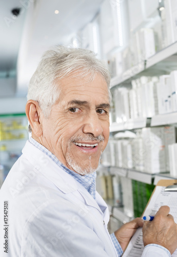 Smiling Senior Pharmacist Counting Stock In Drugstore