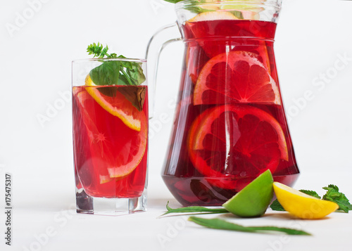 tasty and juicy sangria with citrus in a glass next to the pitcher on a white background. photo