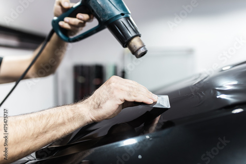 Car tinting - Worker applying tinting foil on car window.