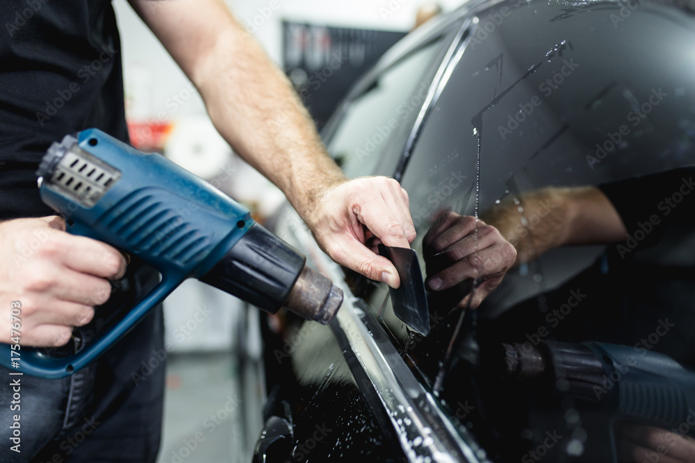 Car tinting - Worker applying tinting foil on car window. Car tinting - Worker applying tinting foil on car window.