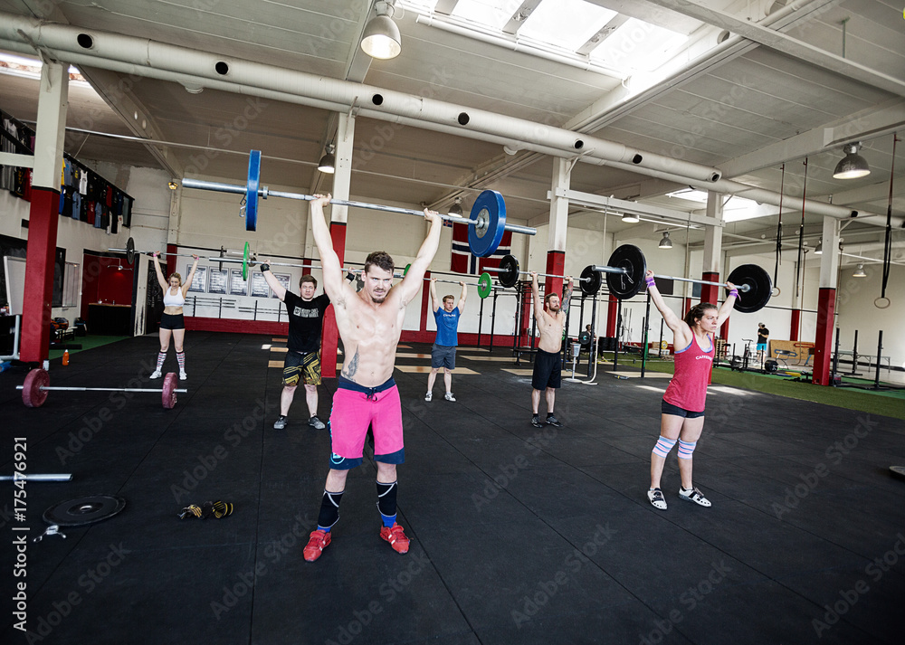 Sporty Men And Women Lifting Barbells