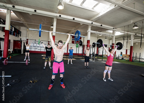 Sporty Men And Women Lifting Barbells