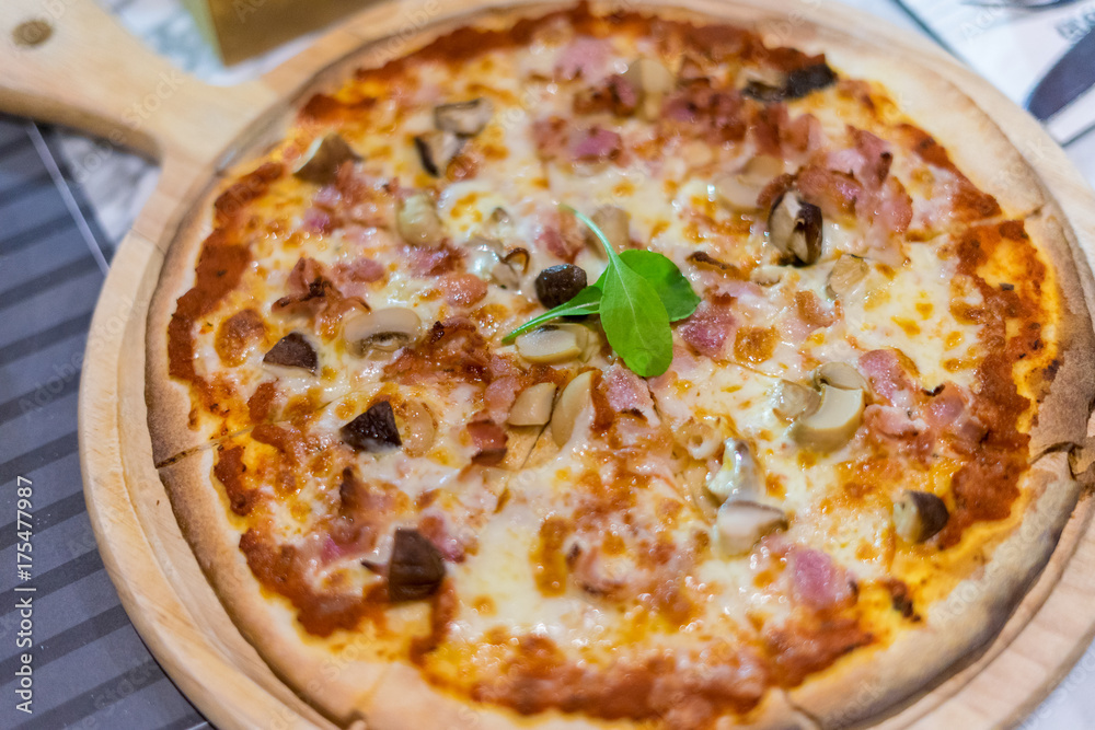 Delicious hot Baked Pizza with sliced Mushrooms, Cheese and Tomato sauce in wooden tray.