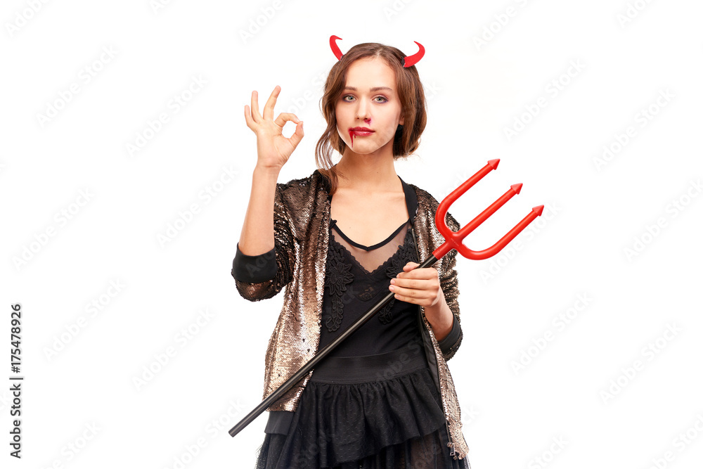 Portrait of beautiful she-devil posing with trident on Halloween against white background