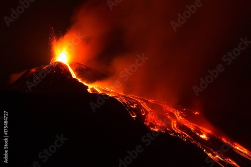 Eruzione sul vulcano Etna con lunga colata di lava vista di notte photo