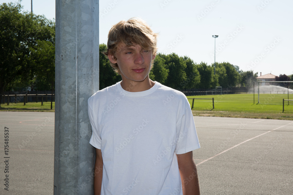 Teenager leaning against pole next to stadium