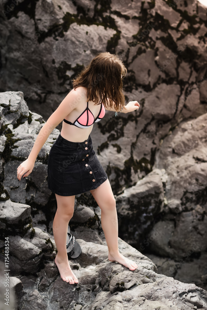 Teenage girl stands on big stones