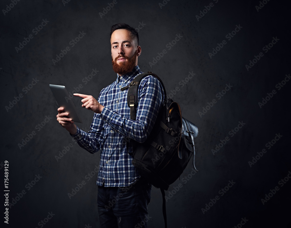 A man holds tablet PC and a backpack. - obrazy, fototapety, plakaty 