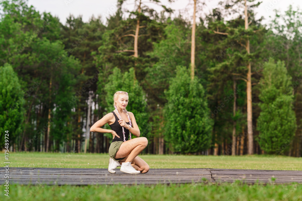 Young female stretching before fitness training session at the park. Healthy young woman warming up outdoors. She is stretching her arms and looking away,hi key.