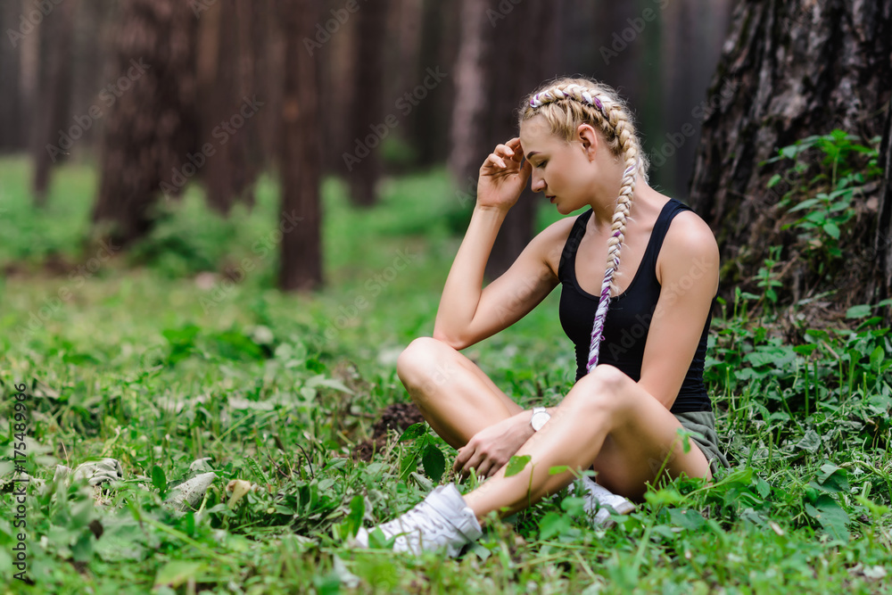 Beautiful slender girl with long braids, walks in the park among the pines Beautiful slender girl with long braids, walks in the park among the pines