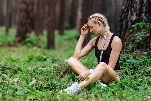 Beautiful slender girl with long braids, walks in the park among the pines