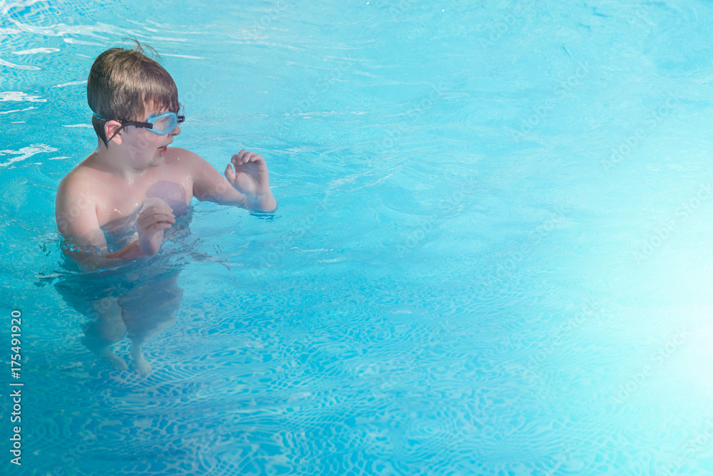 Happy little boy bathing in swimming pool with glasses