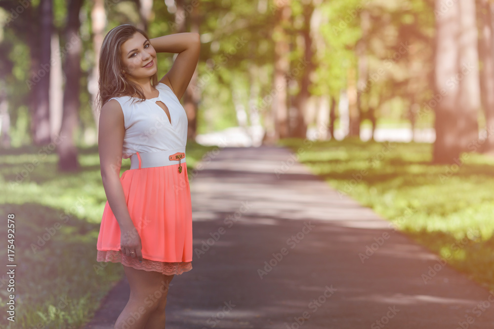 Beautiful girl in white and pink dress walking in the park