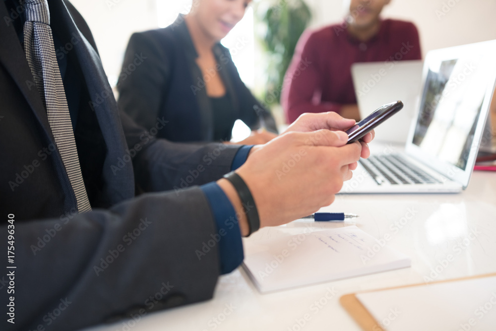 Cropped shot of businessman looking at smartphone during meeting Cropped shot of businessman looking at smartphone during meeting