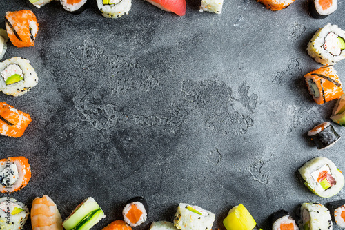 Food frame with set of Japanese food on dark background. Sushi rolls, nigiri, raw salmon steak, rice, and avocado. Flat lay. Top view
