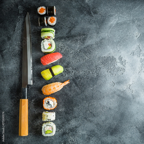 Japanese food - sushi, rolls, rice with shrimp and knife on a dark table. Flat lay, Top view