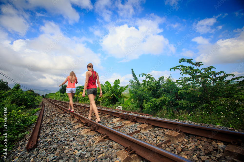 European Girls Walk along Railway under Blue Sky