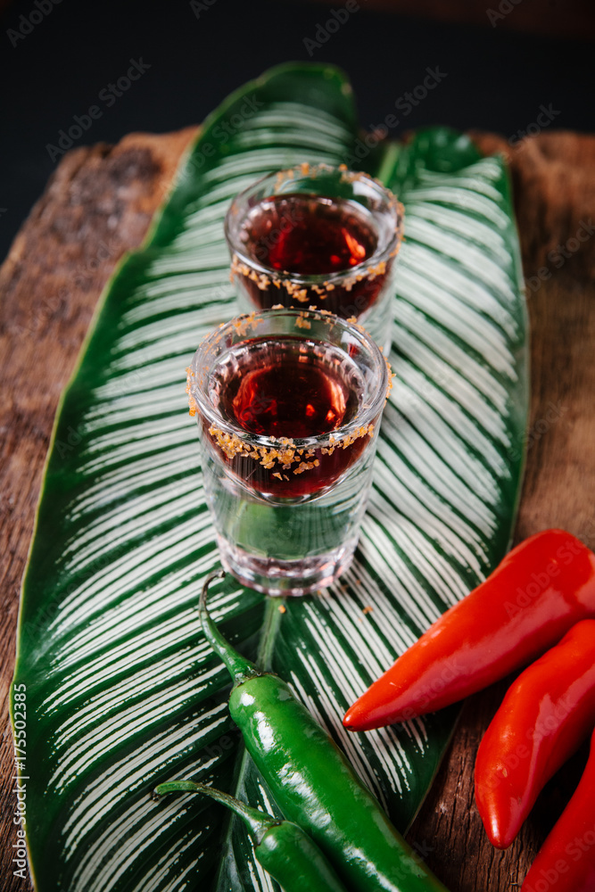 Two spicy tequila shots on rustic background