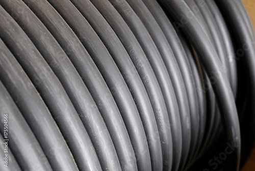 Black wire electric cable on wooden reel.