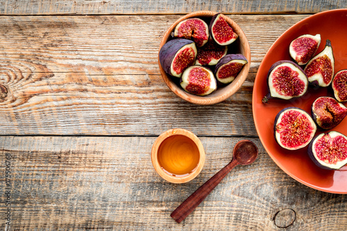 Fototapeta Naklejka Na Ścianę i Meble -  Fresh blue figs in bowl and honey on wooden background top view copyspace