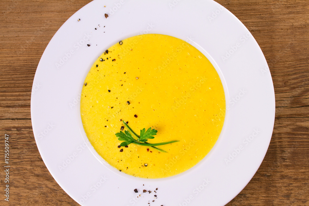 Creamy corn soup in white bowl, garnished with pepper, scallion and parsley. Vegetable soup. View from above, top studio shot, horizontal Creamy corn soup in white bowl, garnished with pepper, scallion and parsley. Vegetable soup. View from above, top studio shot, horizontal