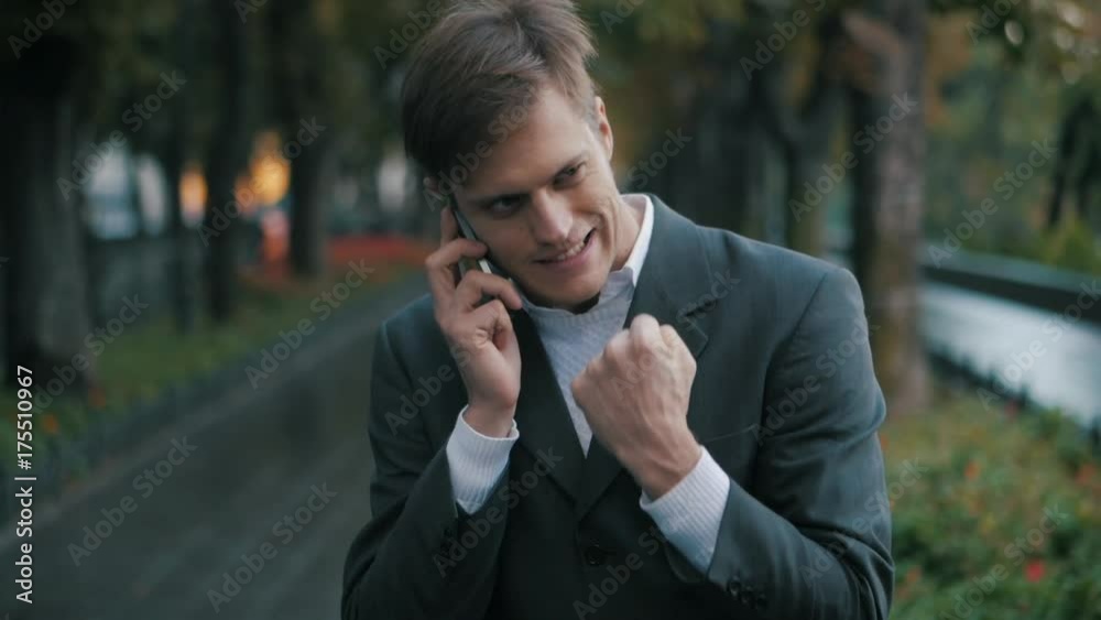 Young handsome businessman talking on mobile phone in the city. Guy heard good news and he is happy. Success concept. The joy of speaking on the phone. Slow motion. Young handsome businessman talking on mobile phone in the city. Guy heard good news and he is happy. Success concept. The joy of speaking on the phone. Slow motion.
